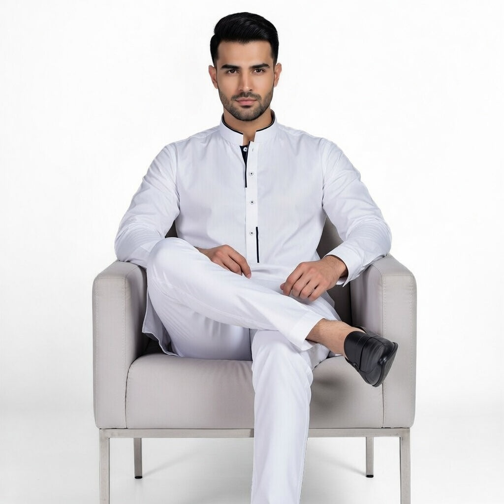 Man wearing a white traditional outfit sitting on a gray chair against a white background