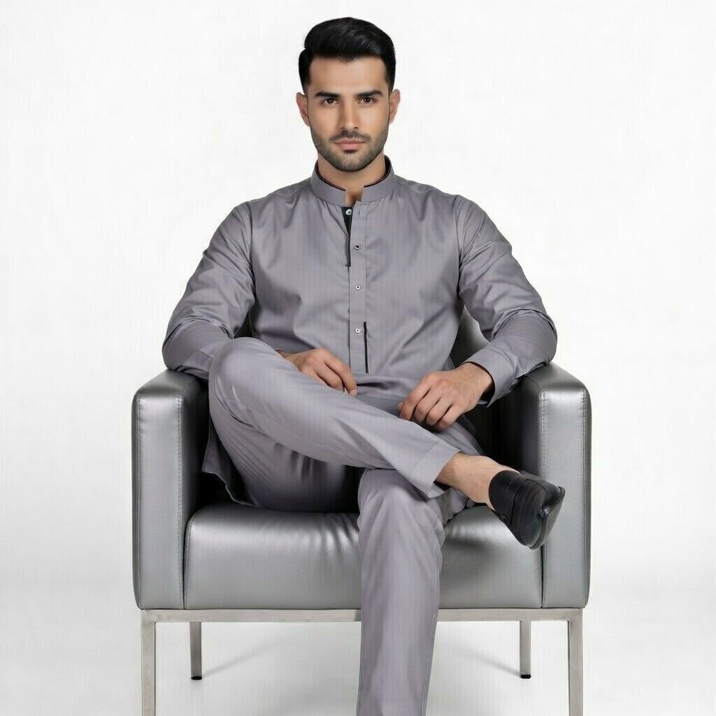 Man sitting on a gray chair wearing a gray outfit against a white background