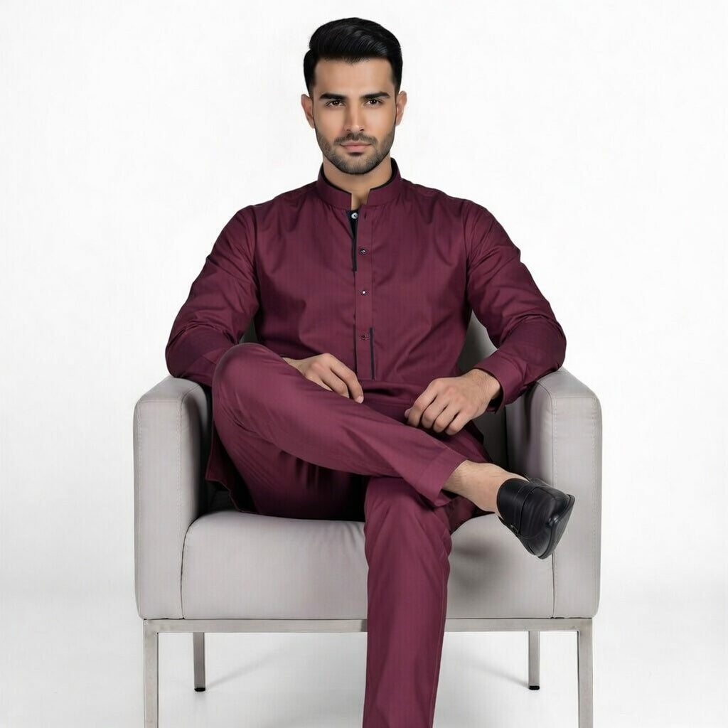 Man sitting on a chair wearing a maroon outfit with a white background