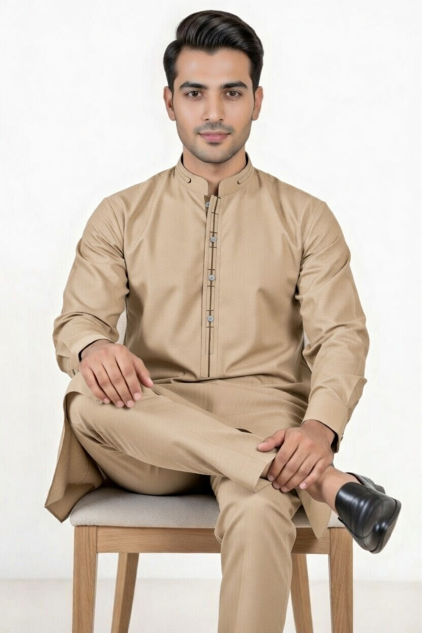 Man wearing a beige traditional outfit sitting on a chair with a white background