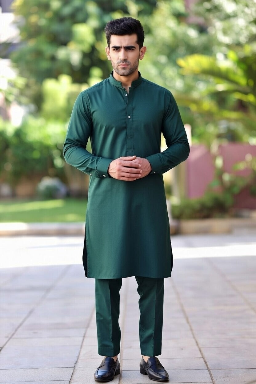 Man wearing a green kurta with black shoes standing outdoors.