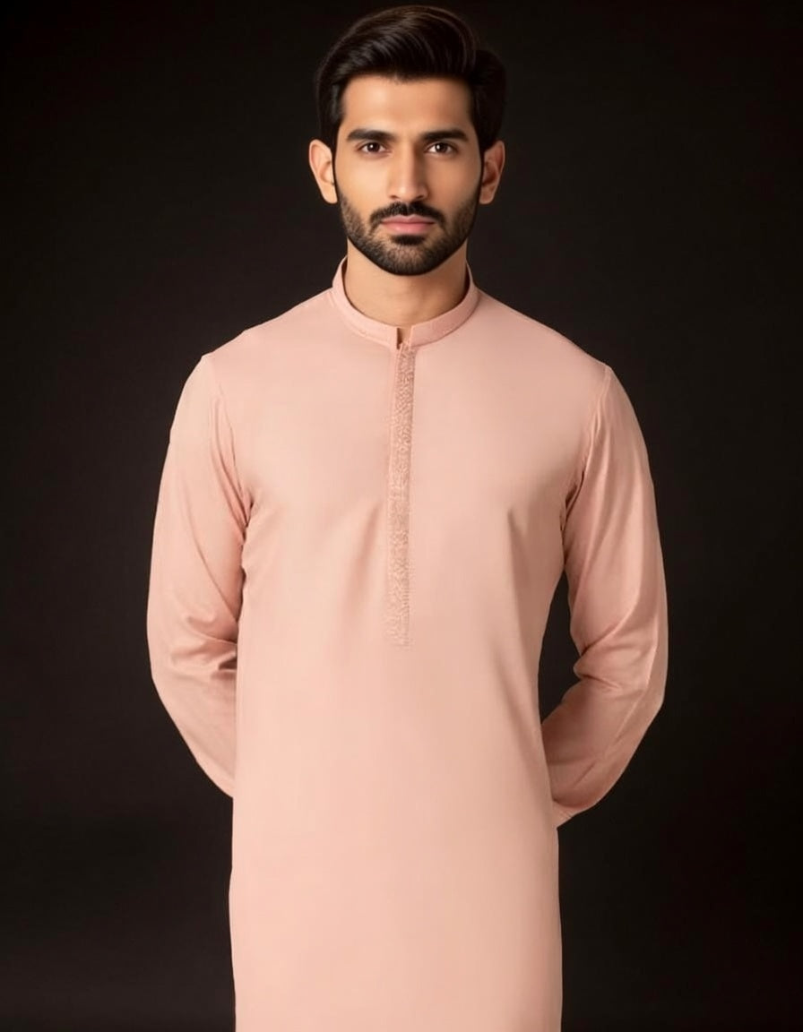 Man wearing a light pink traditional outfit against a black background