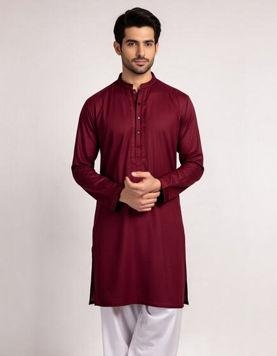 Man wearing a maroon kurta with white pants on a light gray background