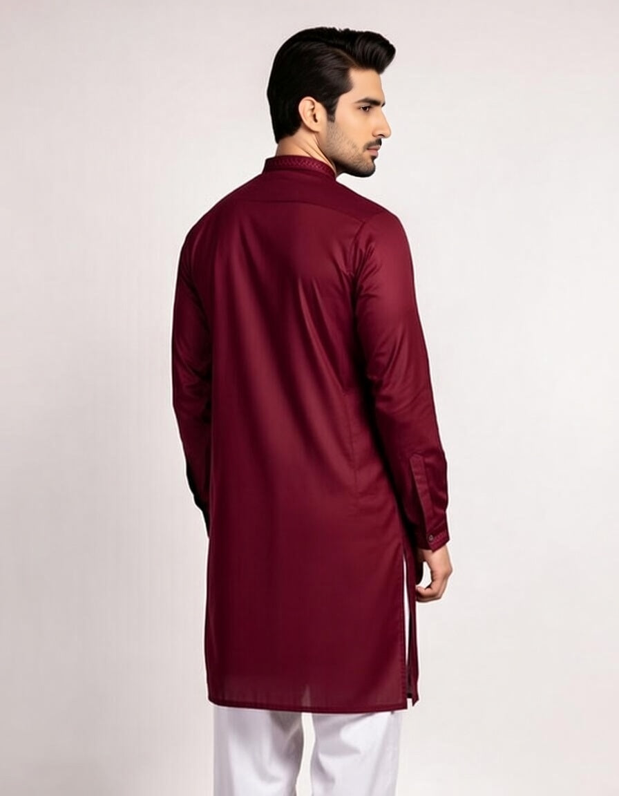 Man wearing a maroon kurta with white pants on a light gray background