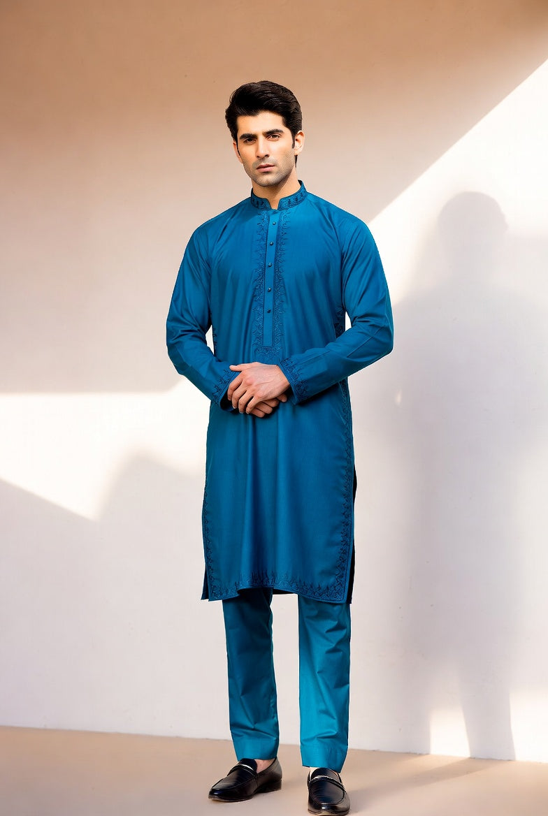 Man wearing a blue kurta with black shoes against a neutral background