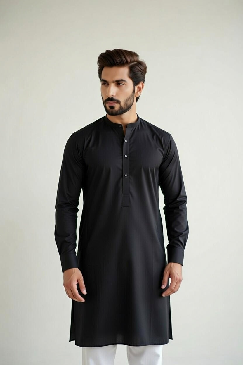 Man wearing a black kurta with white pants against a plain background