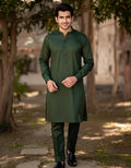 Man wearing a green kurta with black pants standing outdoors.