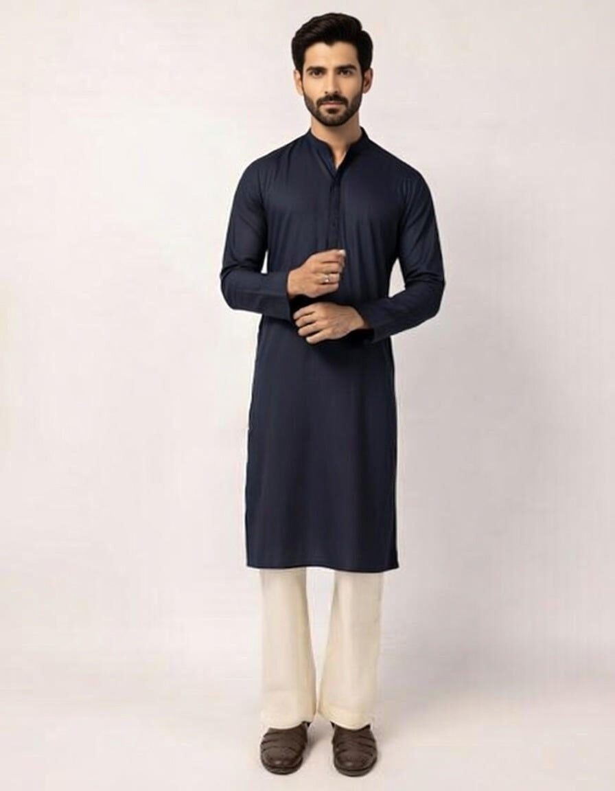 Man wearing a navy kurta with white pants on a light gray background
