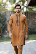 Man wearing a mustard yellow kurta with intricate embroidery outdoors.